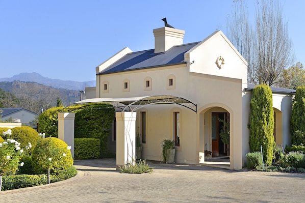 A two-story building with a covered entrance, a chimney, and a view of mountains in the background.