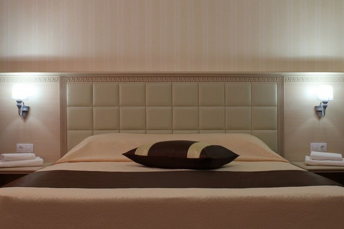 A hotel room with a large bed, two nightstands, and a headboard with a geometric pattern.