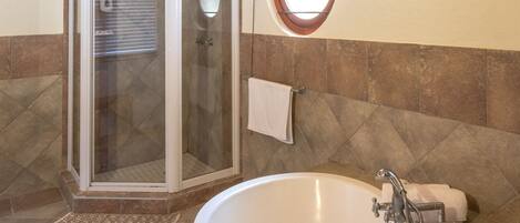 A bathroom with a glass-enclosed shower, a freestanding bathtub, and a vanity with a mirror.