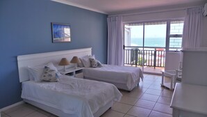 A hotel room with two beds, a balcony with a view, and a painting on the wall. - The Chapman Hotel & Conference Centre (Gqeberha (Port Elizabeth))