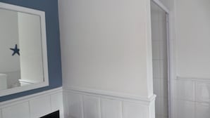 A bathroom with a white vanity, a mirror, and a blue accent wall. - The Chapman Hotel & Conference Centre (Gqeberha (Port Elizabeth))