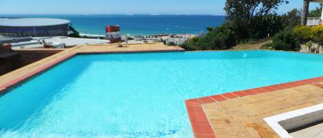 A swimming pool with a view of the ocean and a stadium in the background.