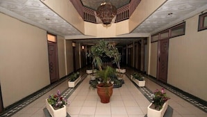 A spacious hallway with a central plant arrangement, tiled floor, and a decorative ceiling. - Hôtel Ichbilia (Marrakech)