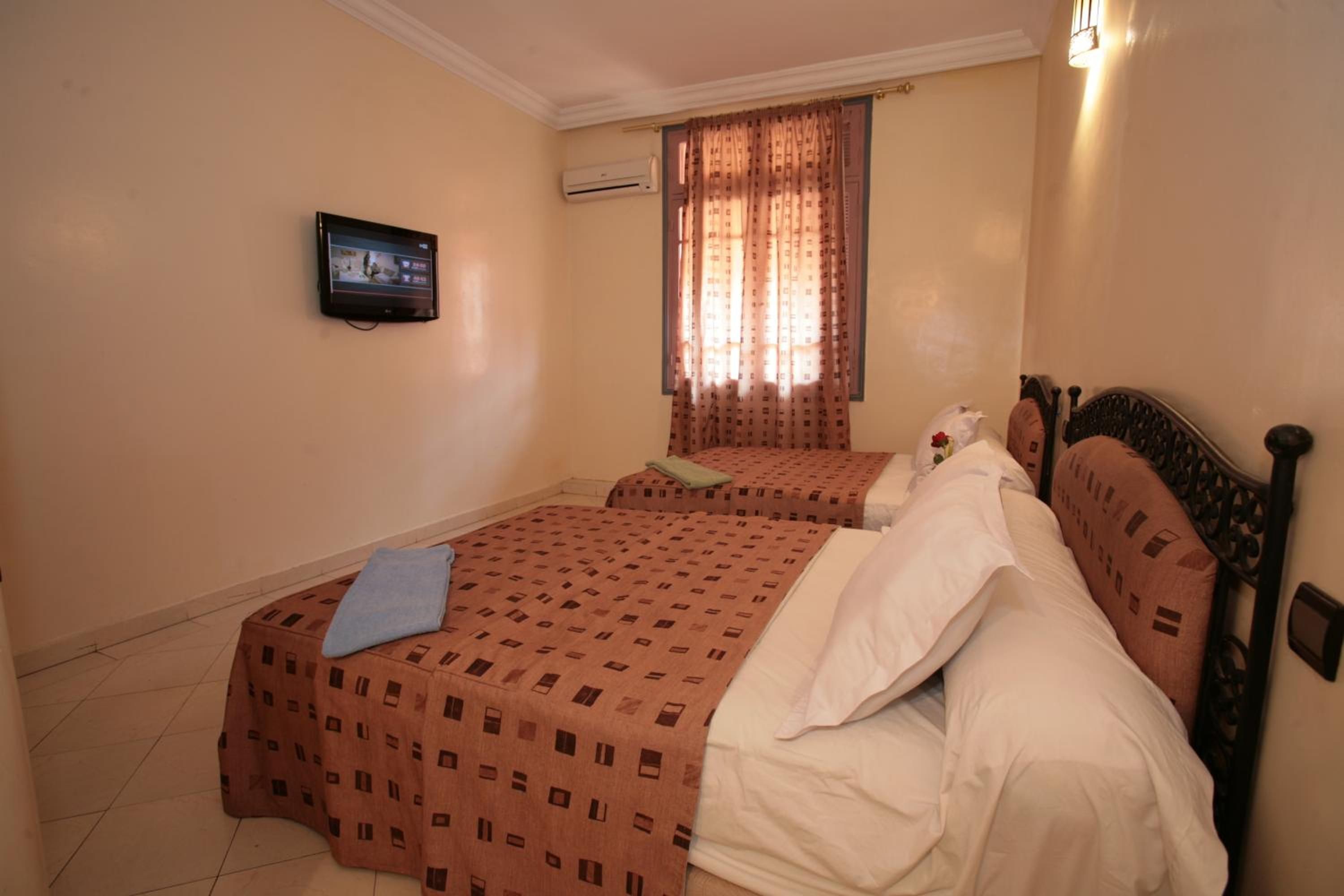 Habitación de hotel con dos camas, un televisor, un aire acondicionado y una ventana con cortinas.