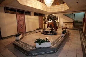 A spacious lobby with a central fountain, potted plants, and a staircase. - Hôtel Ichbilia (Marrakech)