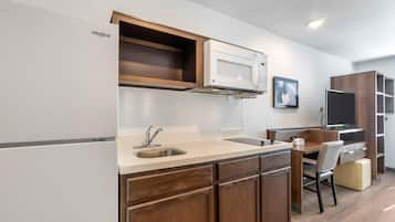 A compact kitchen with a built-in microwave, a sink, and wooden cabinets.