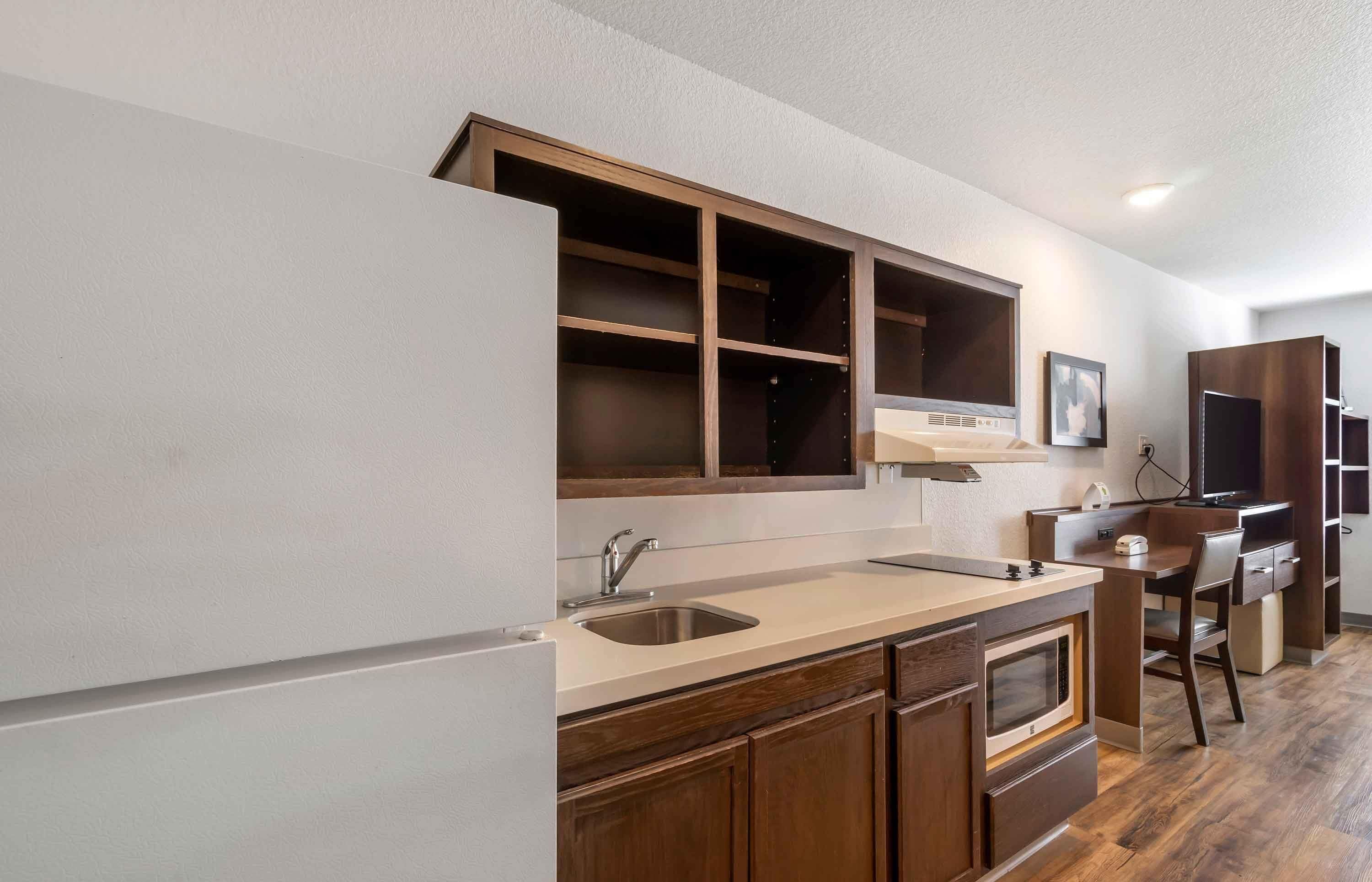 A kitchen with wooden cabinets, a double sink, and a microwave.