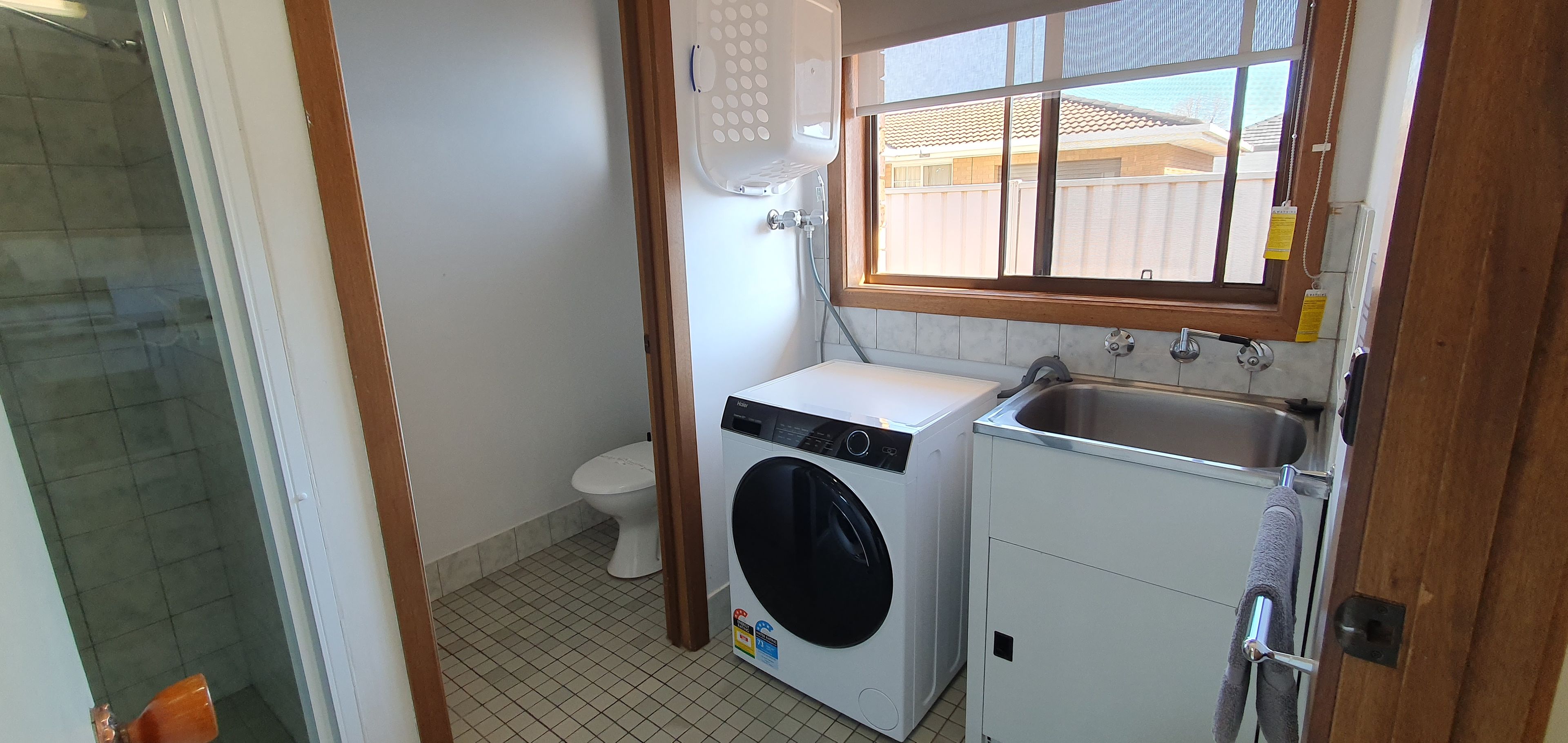 Een kleine wasruimte met een wasmachine, een wastafel en een toilet.