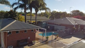 Ett bostadsområde med ett hus i tegel, en täckt uteplats och en swimmingpool.