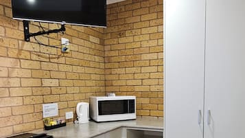 Ett kompakt kök med en platt-TV, en mikrovågsugn och en diskmaskin.