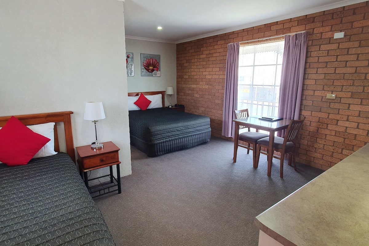 A hotel room with two beds, a desk, and a chair.