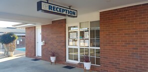 A reception area with a sign, a brick wall, and a window. - Centrepoint Motel (Deniliquin)