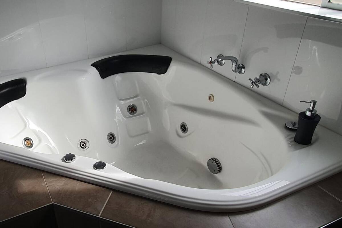 A modern bathroom with a freestanding bathtub, a towel rack, and a toilet.