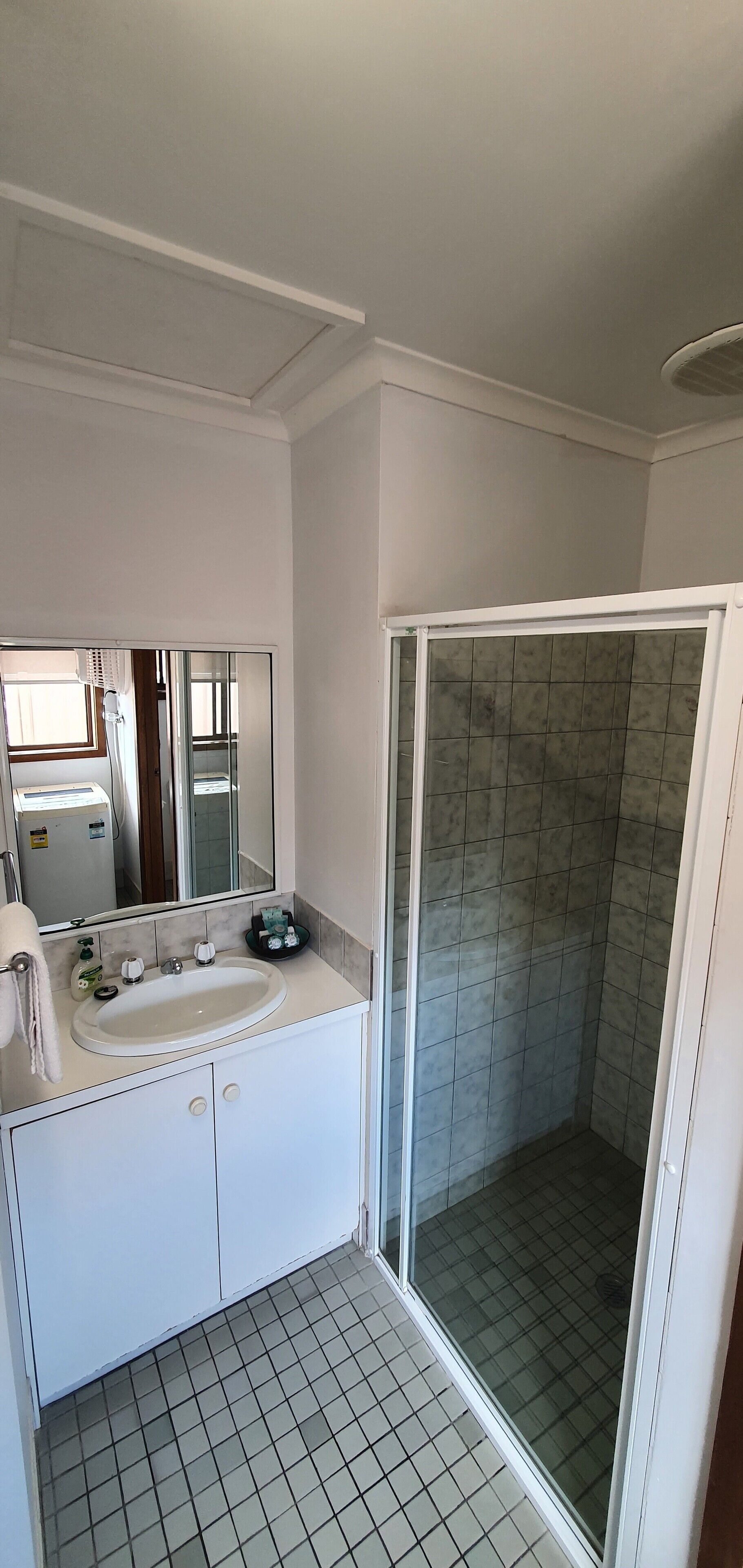 A bathroom with a white sink, mirror, and tiled floor.