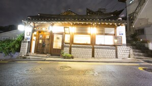 Een traditioneel Japans gebouw met een houten gevel, een pannendak en een verlichte ingang.