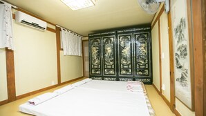 Een kamer met een bed, een airconditioner, een ventilator en een raam met uitzicht op bomen.