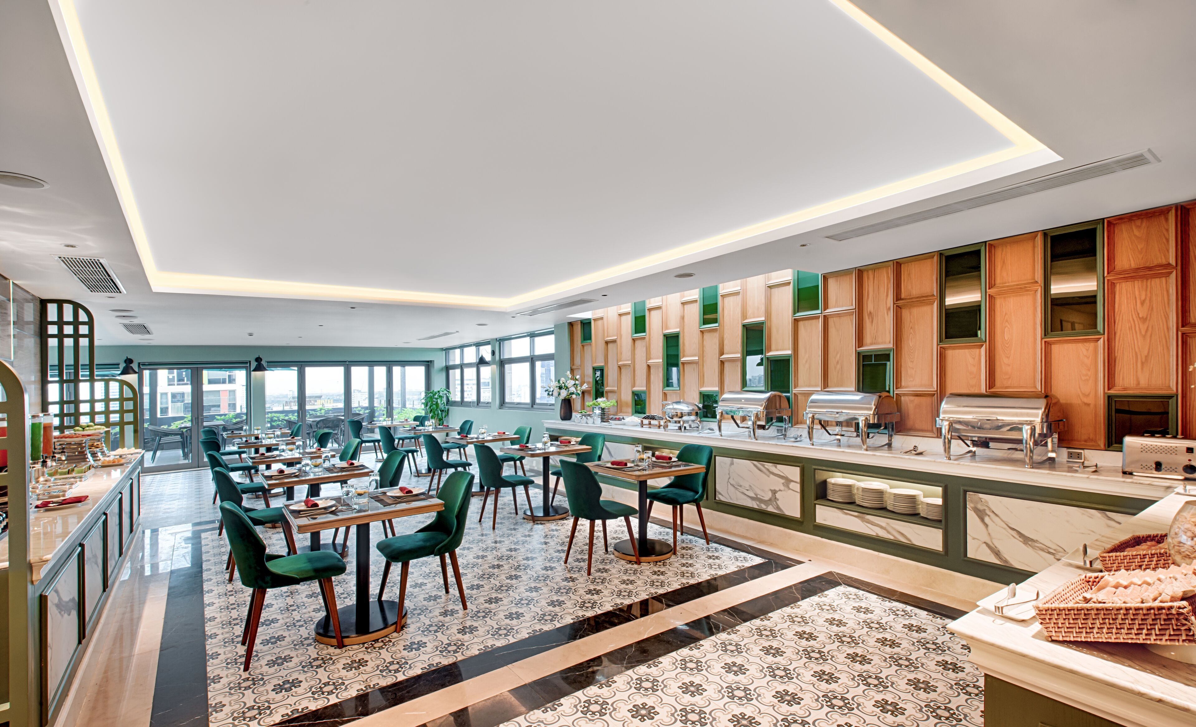 Un restaurante moderno con una barra larga, sillas verdes y vistas de la ciudad a través de amplios ventanales.