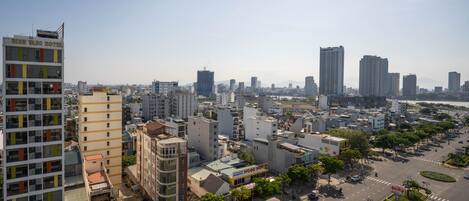 Une vue sur la ville avec un hôtel imposant appelé « Bien Vang Hotel », qui présente un design moderne avec de nombreux étages et des balcons.