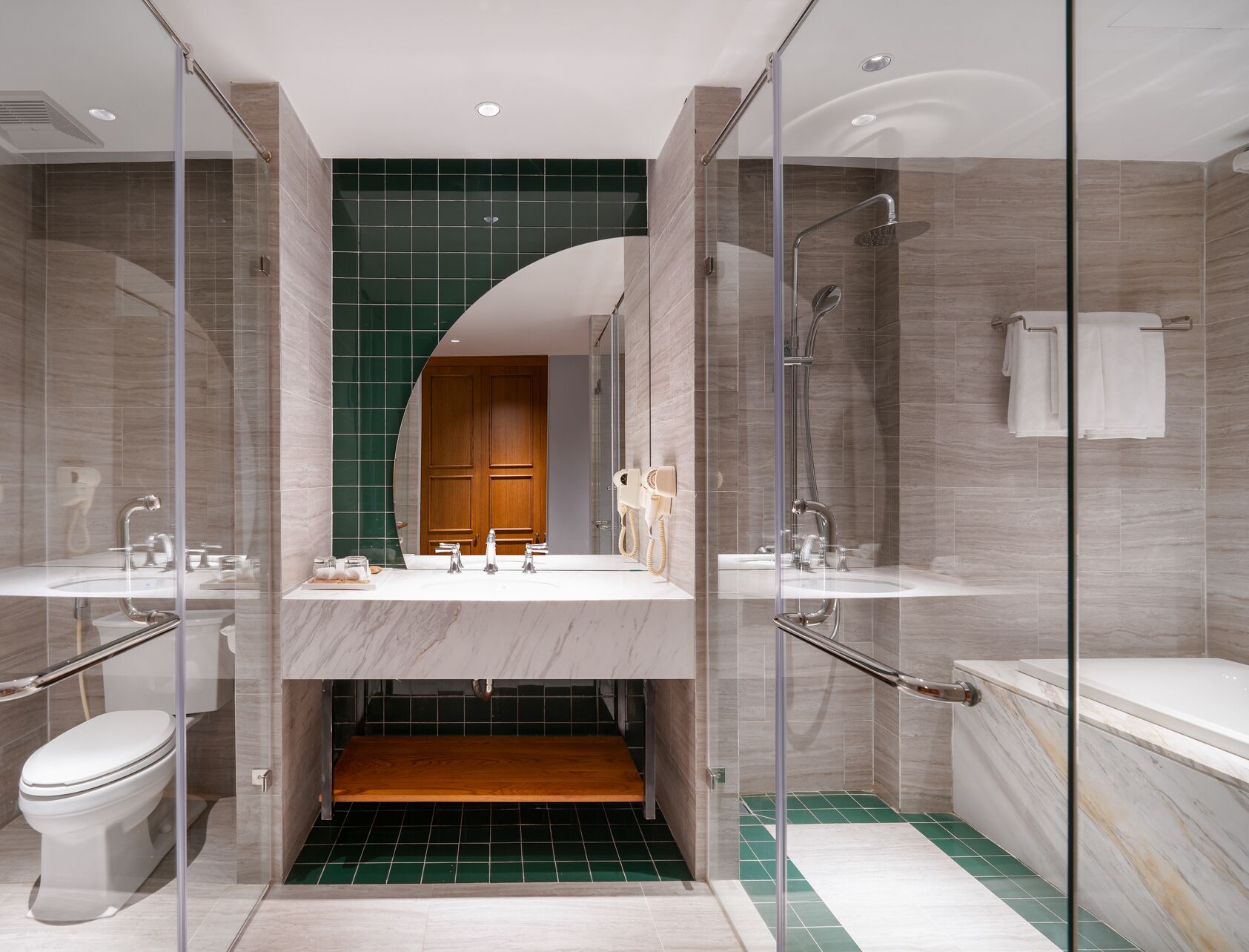 Un baño moderno con ducha de vidrio, dos lavamanos, un inodoro y un mueble de tocador de madera.