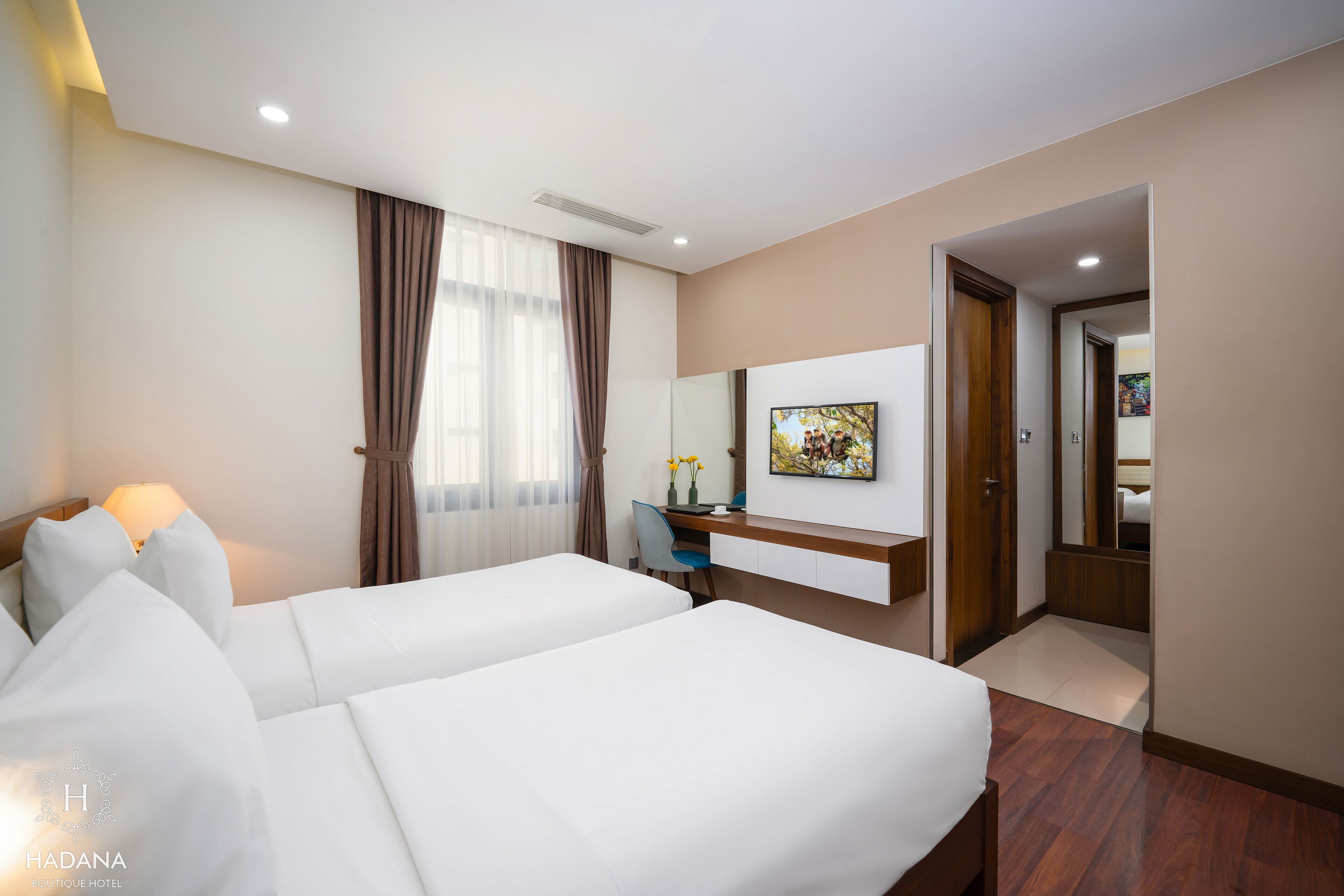 Habitación de hotel con dos camas, un escritorio, una silla, un espejo y un cuadro en la pared.