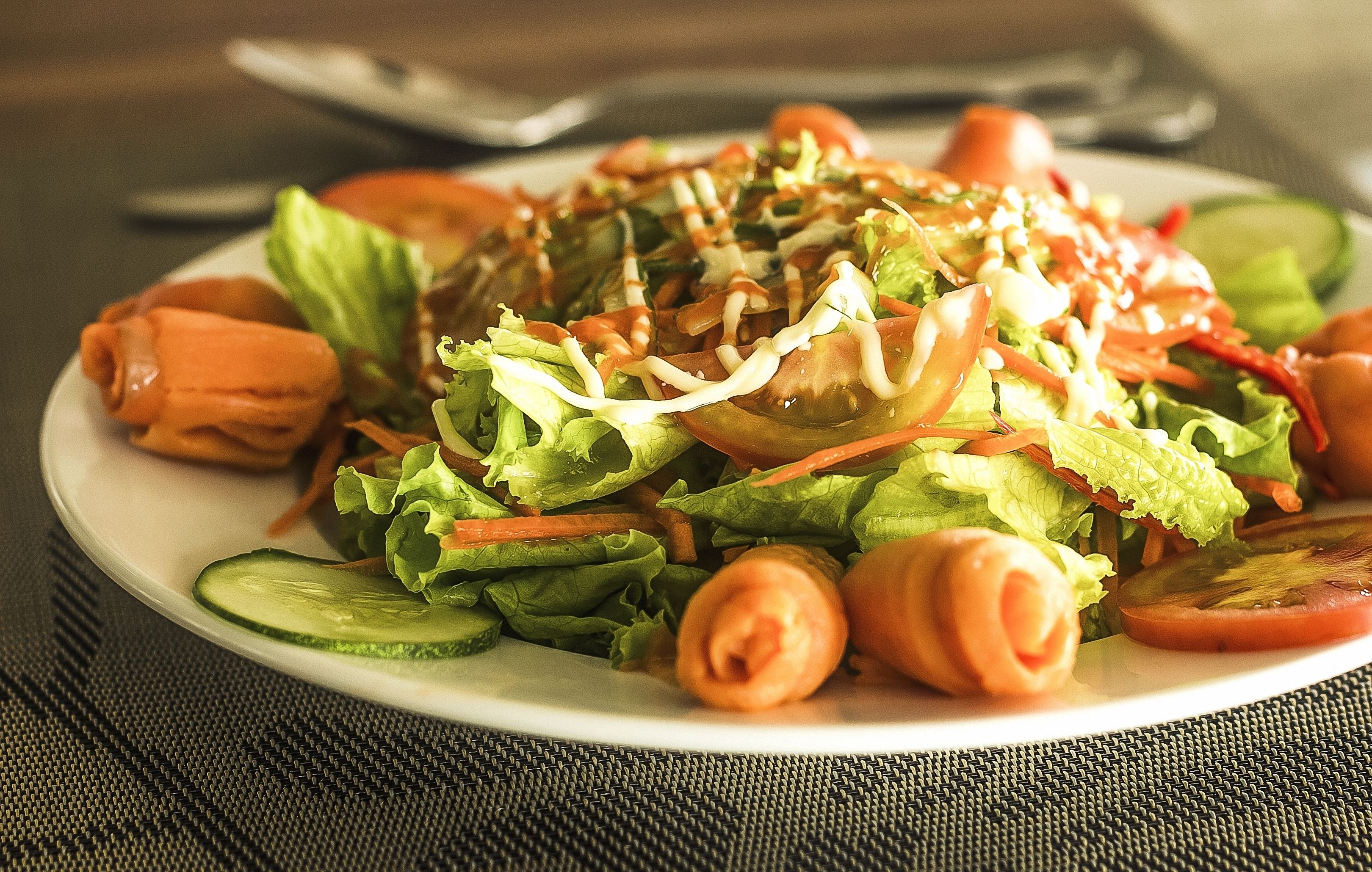 A plate of salad with lettuce, tomatoes, and cucumber slices.