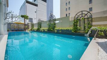 Una piscina al aire libre, sombrillas, sillones reclinables de piscina