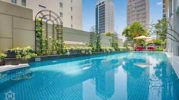 Una piscina al aire libre, sombrillas, sillones reclinables de piscina