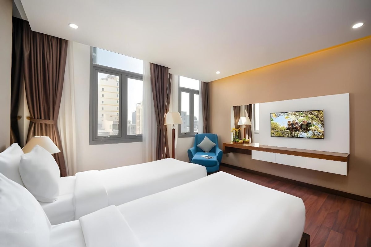 Habitación de hotel con dos camas, televisión, escritorio y una silla.