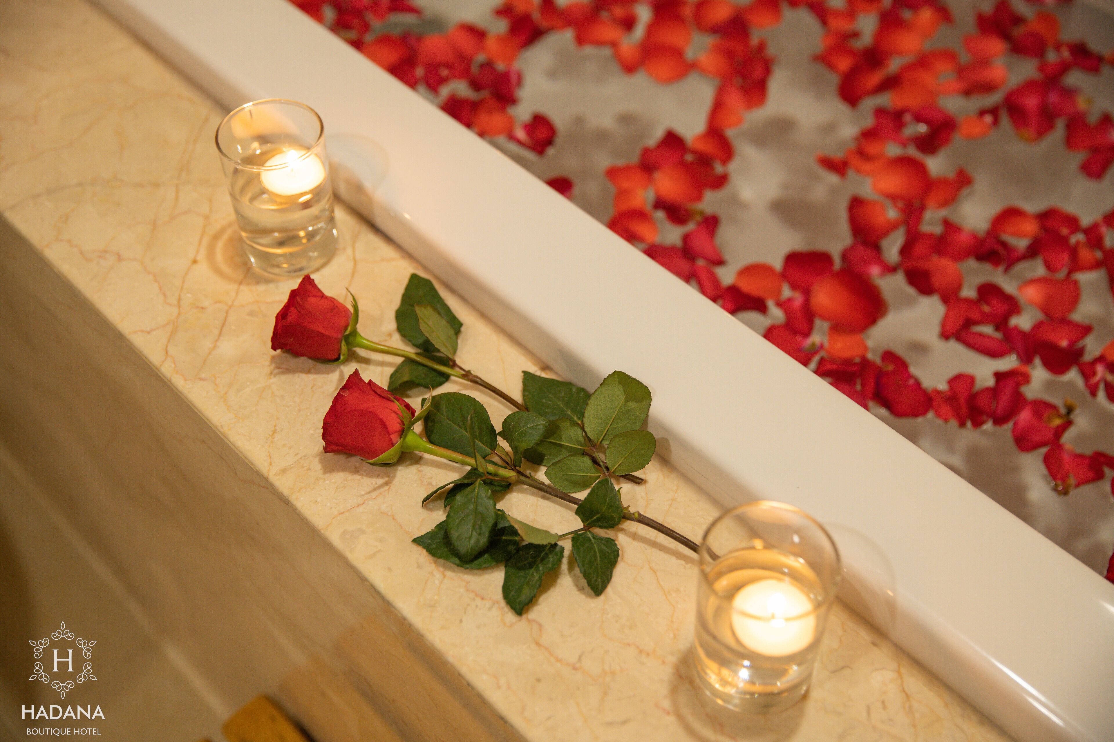 A bathtub with rose petals and candles.