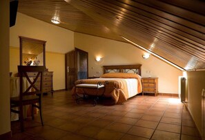 A bedroom with a sloped ceiling, a bed, a dresser, a chair, and a mirror. - Hotel Rural La Plazuela (Aldealengua)