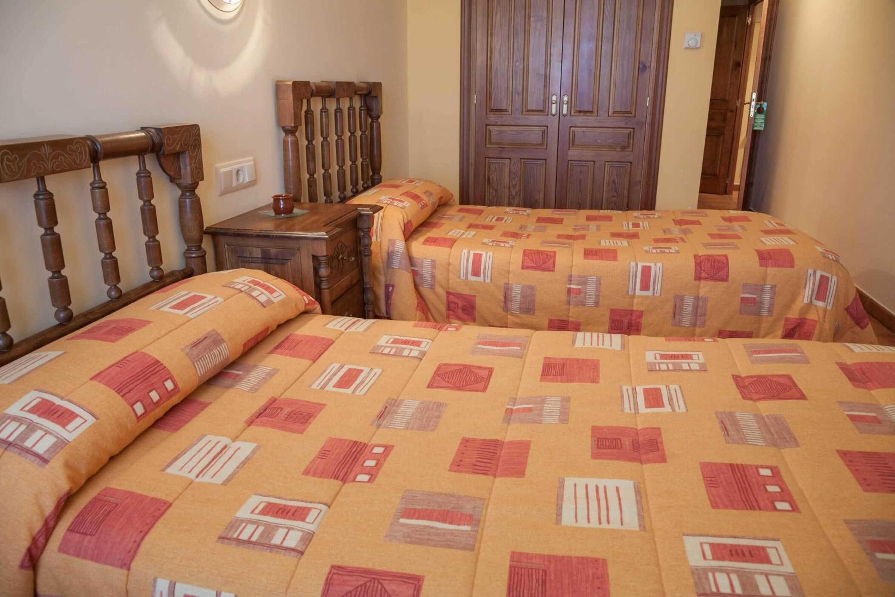 Quarto com duas camas, cabeceiras de madeira e um guarda-roupa.