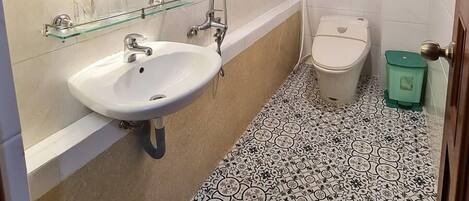 Un baño con lavamanos blanco, un espejo redondo con iluminación, ducha y retrete.