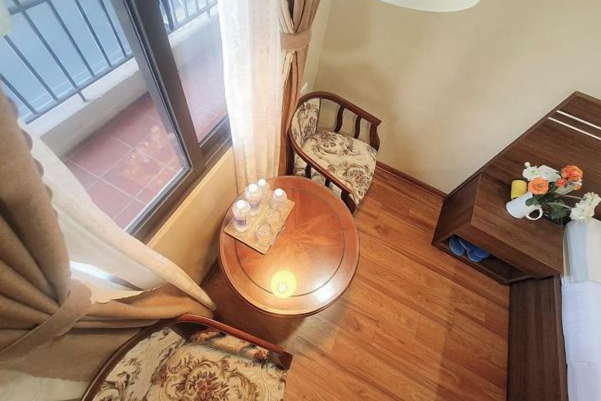 A small, cozy room with a wooden table, a chair, and a small cabinet with decorative items.