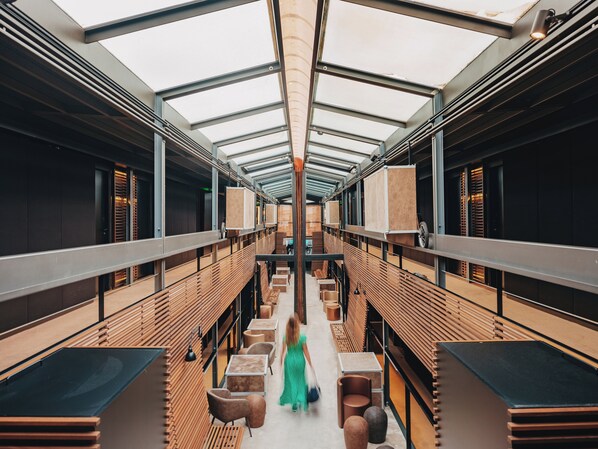 A modern interior with a central walkway, wooden slats, and tables.