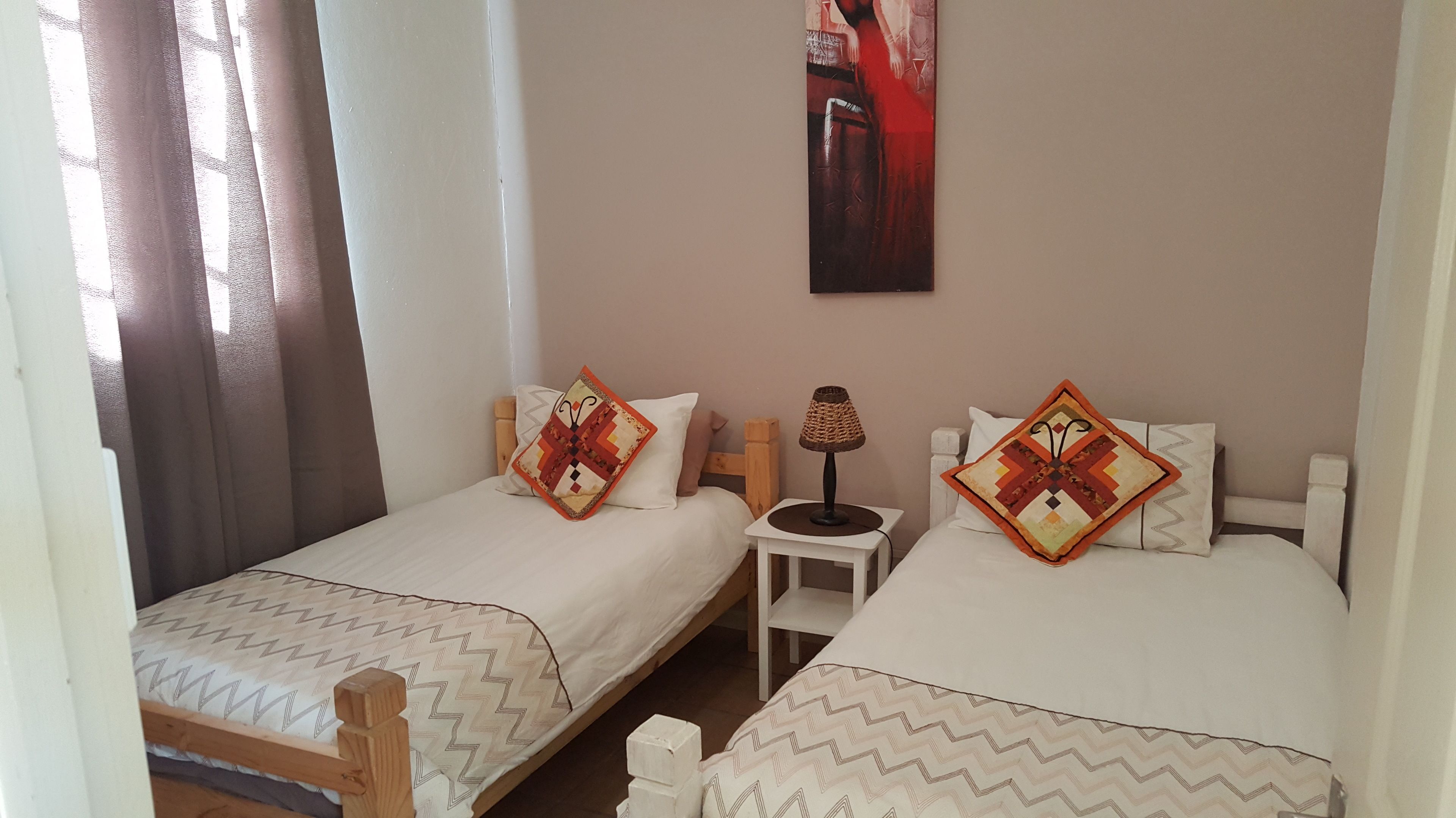 A double room with two single beds, a small table, and a lamp.