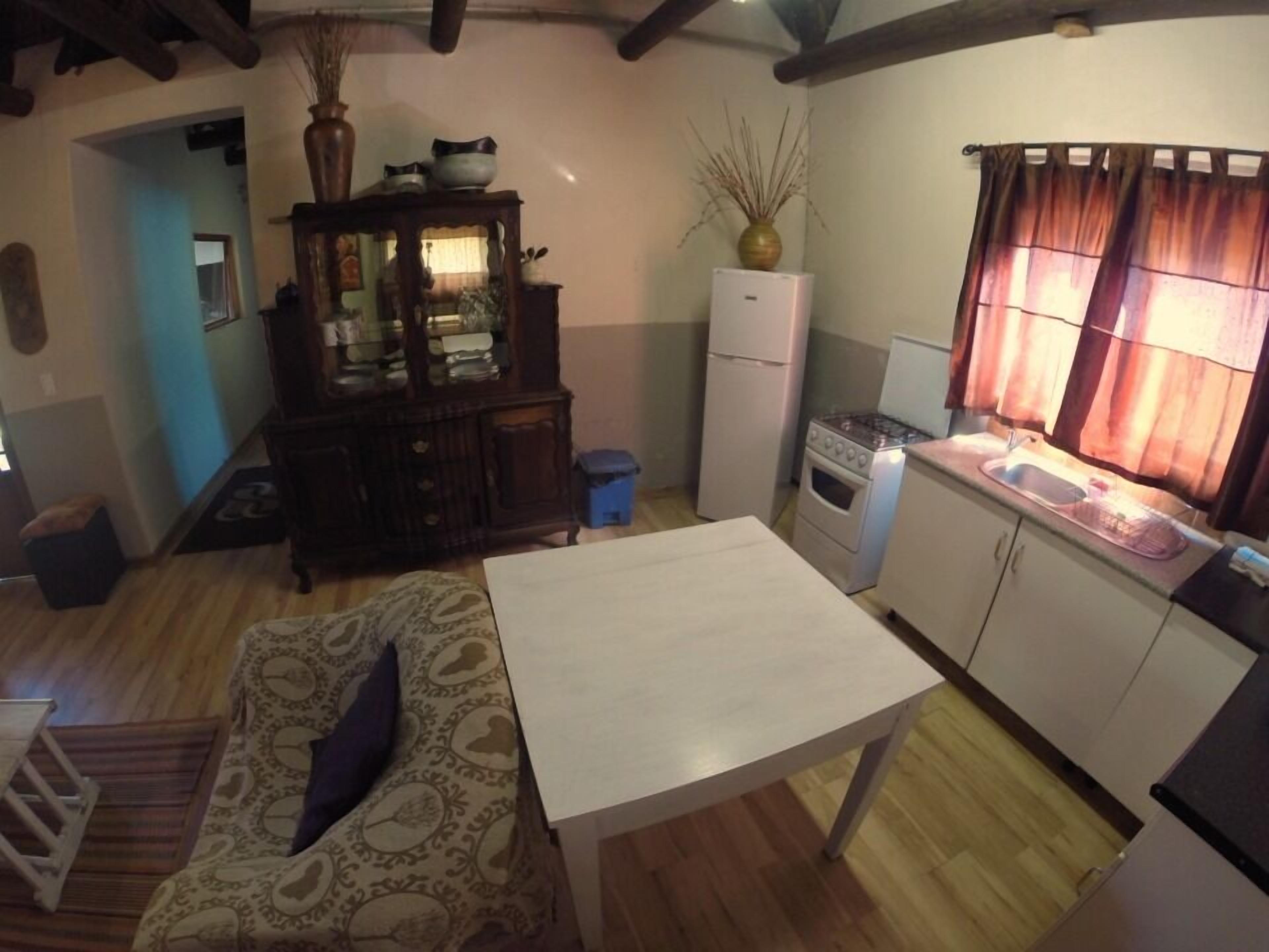 A compact kitchen with a dining area, wooden flooring, and a built-in cabinet.