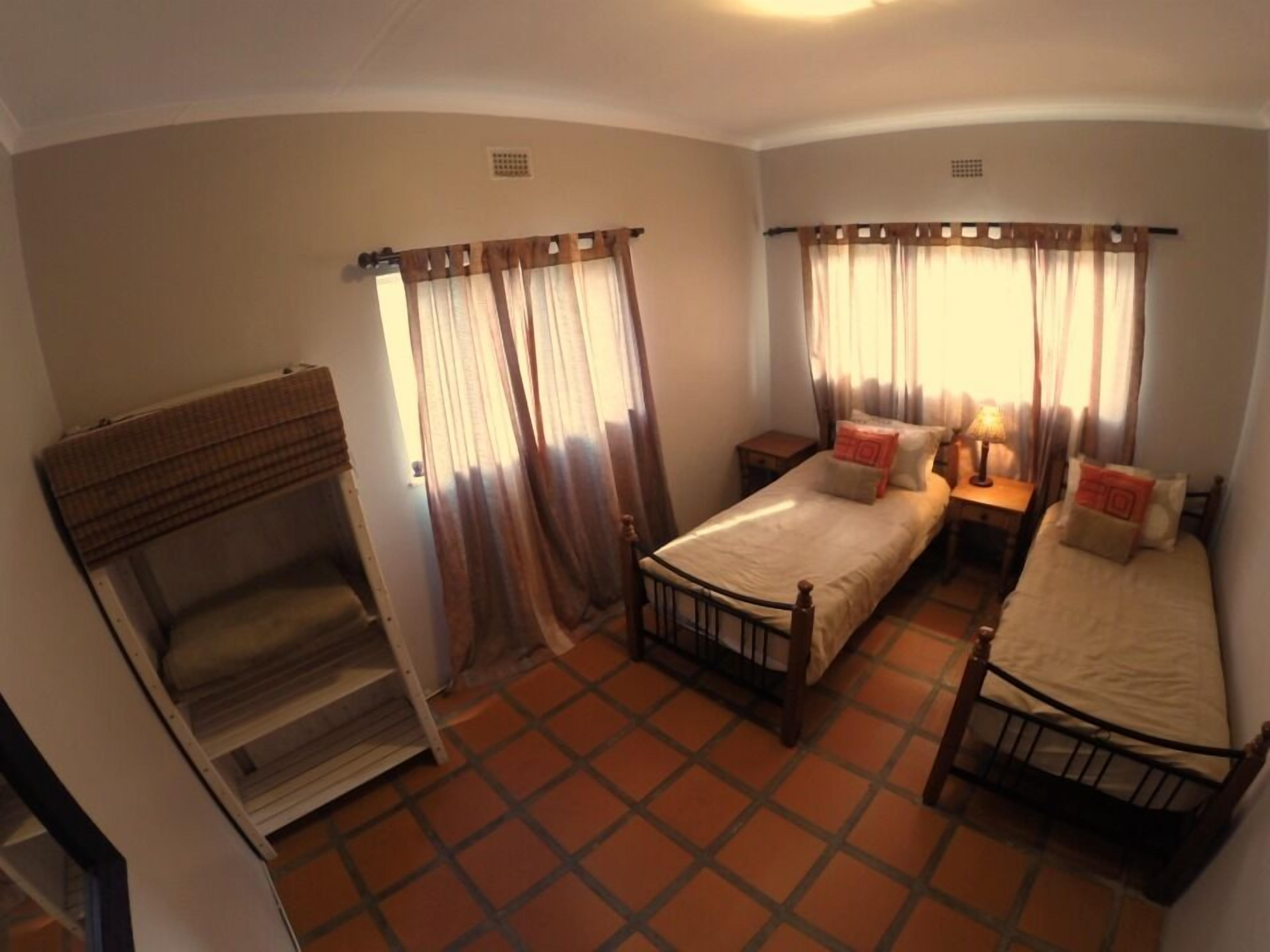 A room with two beds, a small table, and a bench.