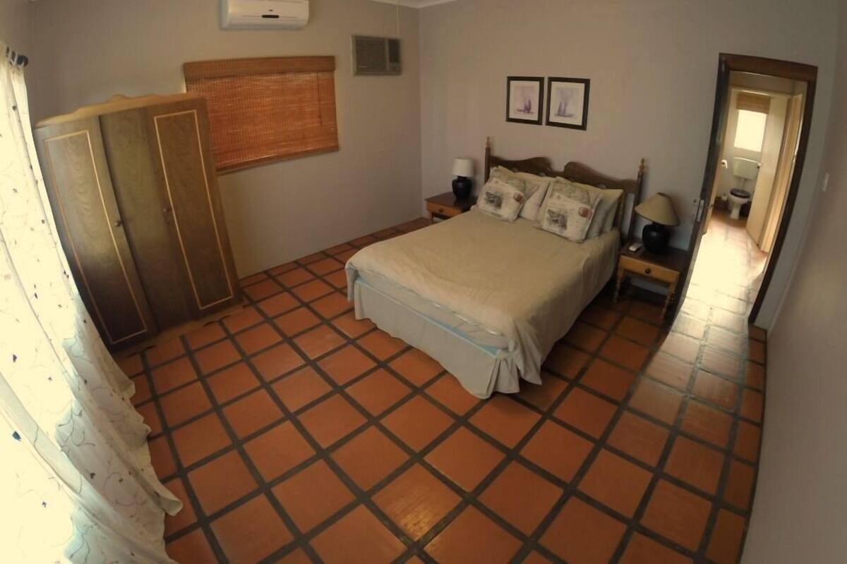 A bedroom with a bed, a nightstand, a wardrobe, and a window with curtains.