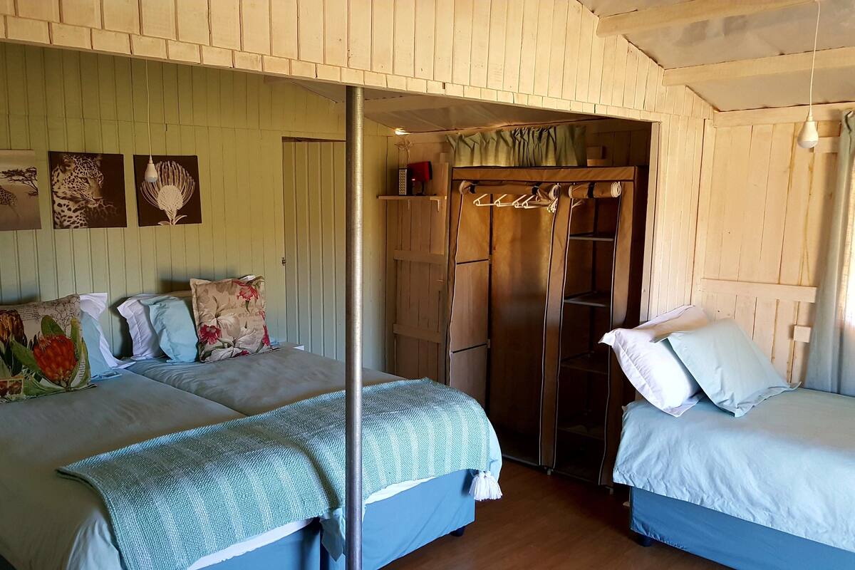 A room with two beds, a wardrobe, and a mirror.