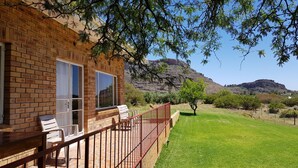 A brick building with a balcony, outdoor seating, and a view of a mountainous landscape. - de Pakhuys (Cederberg)