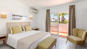 Une chambre d’hôtel moderne dotée d’un grand lit, d’un coin salon et d’un balcon avec vue.