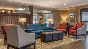 A hotel lobby with a blue sofa, red and grey armchairs, and a patterned rug. - Comfort Inn PA Turnpike - 1-81 (Carlisle)