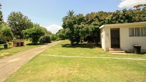 A house with a paved driveway leading to a front door, surrounded by a well-maintained lawn and various trees.