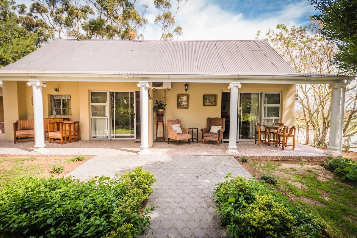 A two-story house with a covered porch, a dining area, and a garden.