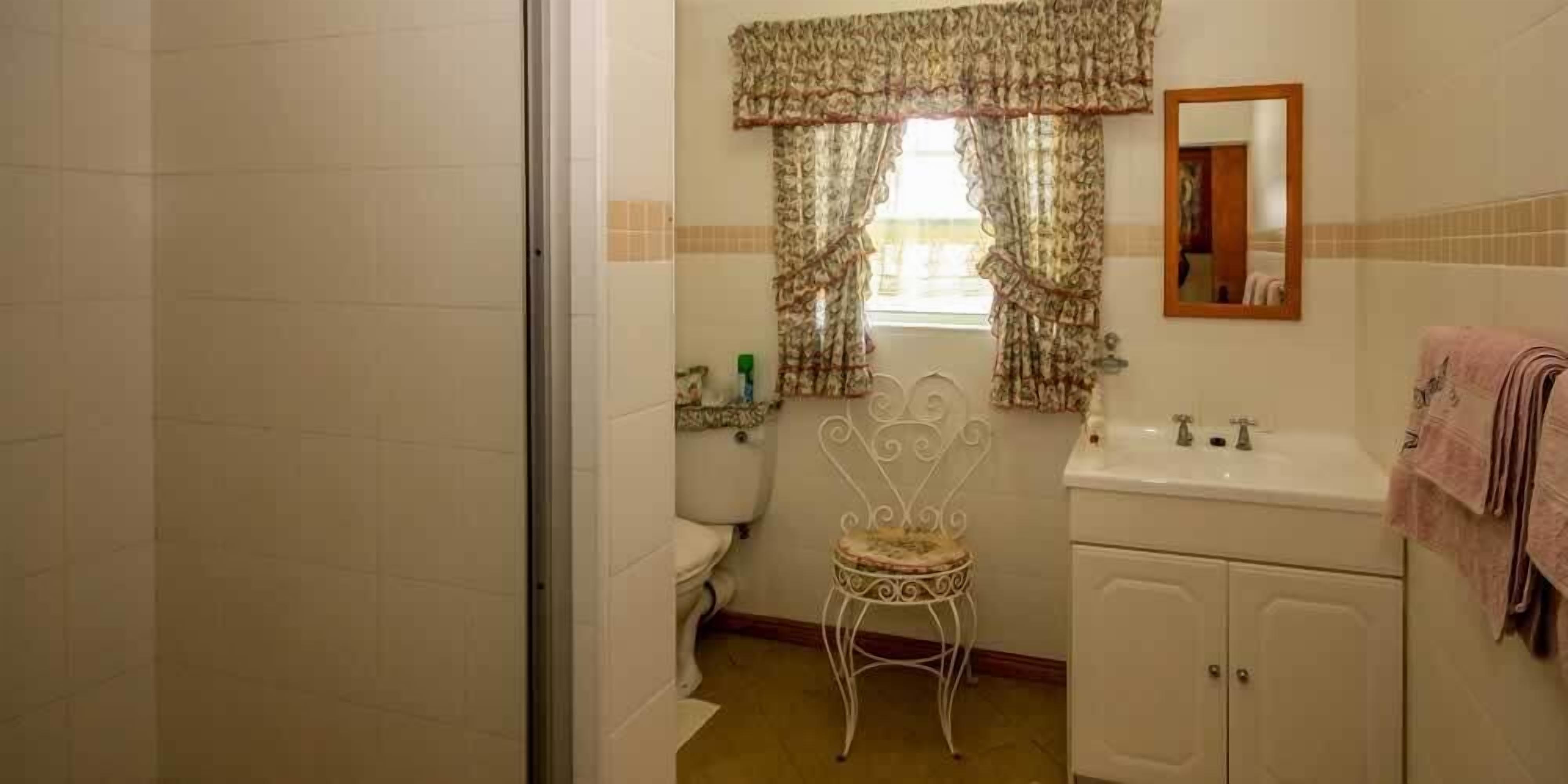 A bathroom with a toilet, sink, and chair.