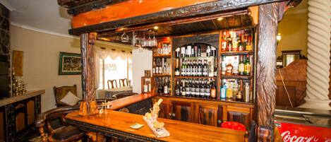 Zona de bar con mostradores de madera, estanterías llenas de botellas de licor y un refrigerador de Coca-Cola.
