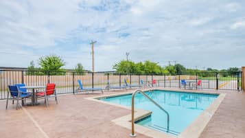 Una piscina al aire libre, sillones reclinables de piscina