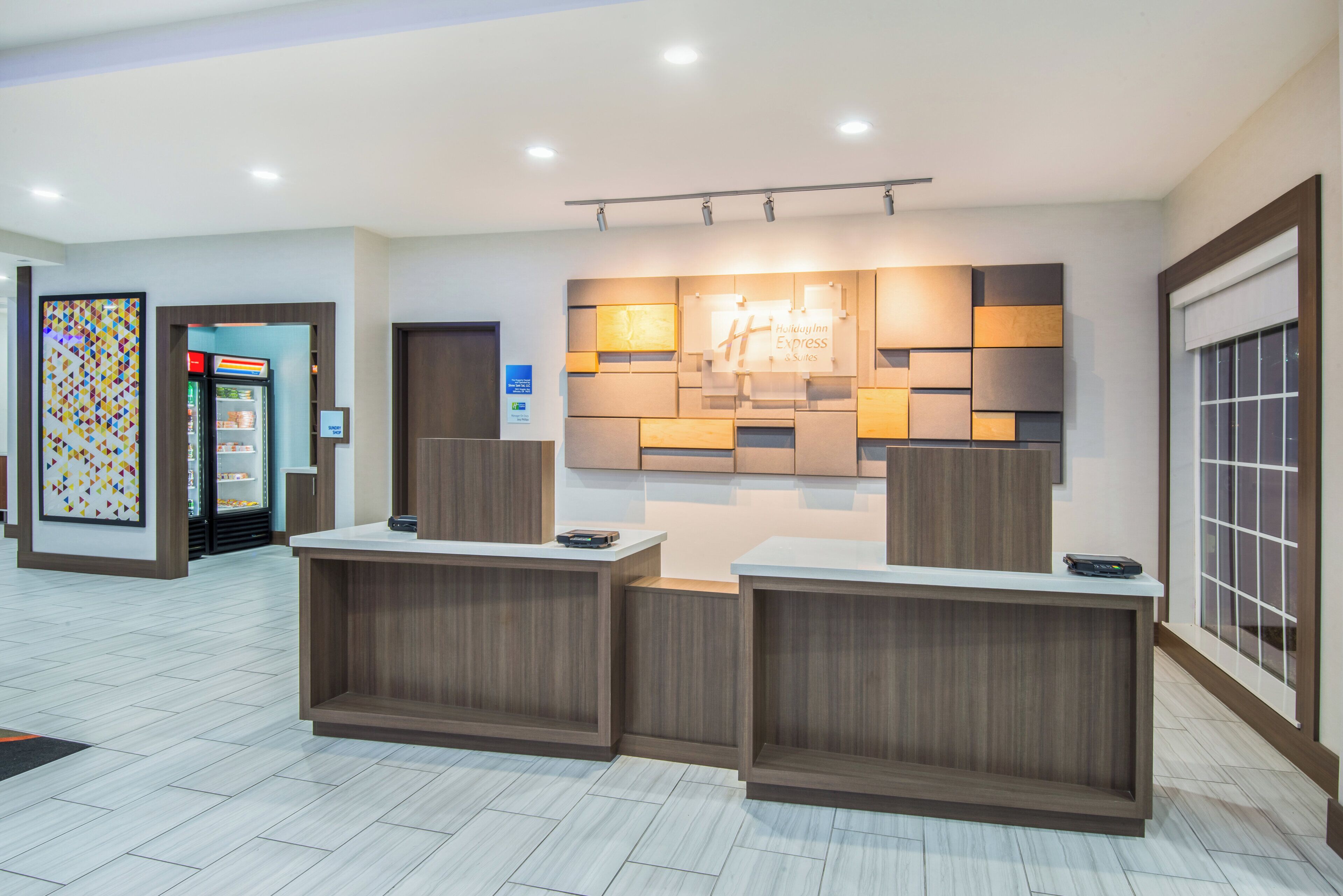Una recepción de hotel con diseño moderno, una pantalla digital y un letrero de Holiday Inn Express & Suites.