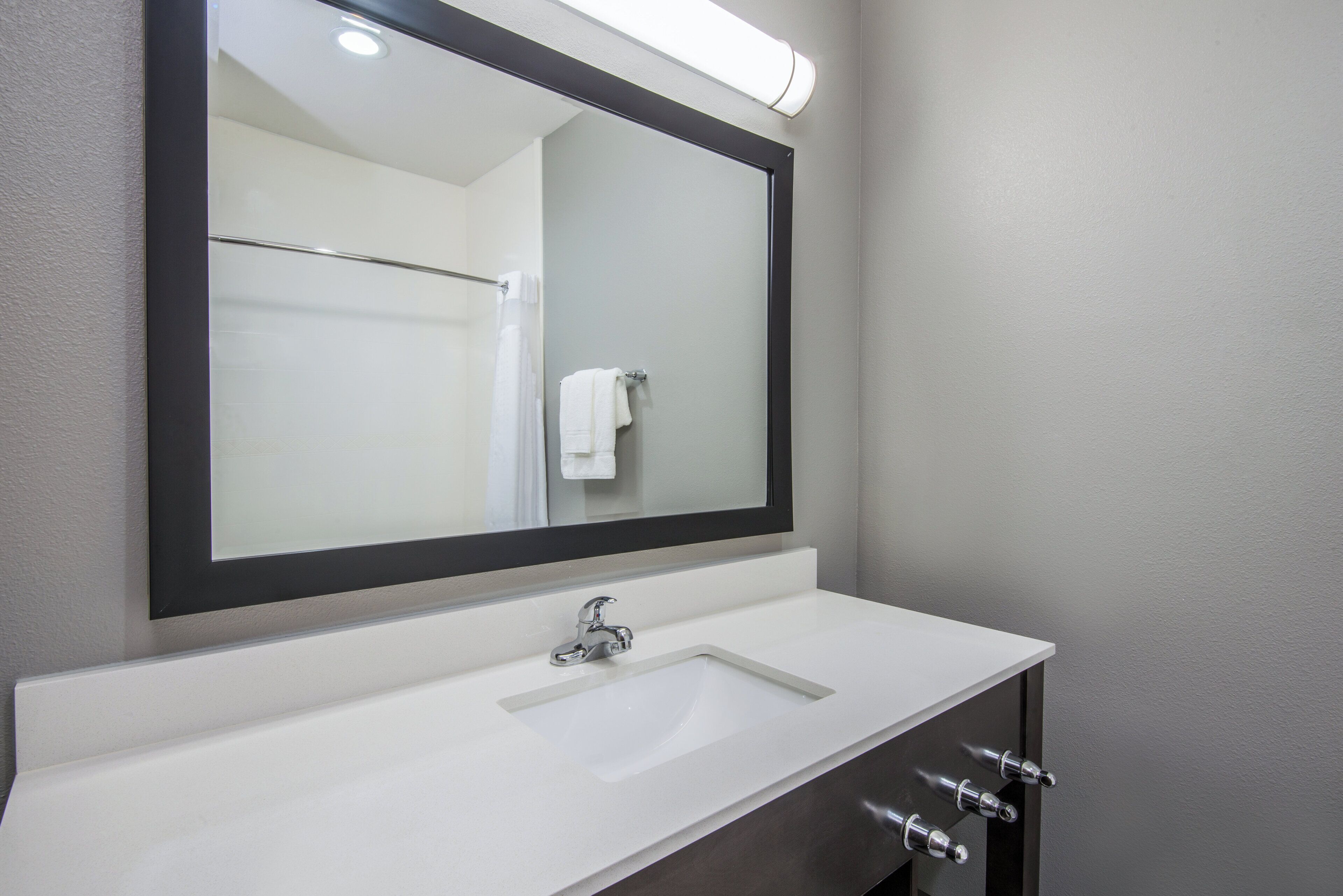 A bathroom with a white sink, a mirror, and a towel rack.