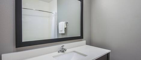 A bathroom with a white sink, a mirror, and a towel rack.